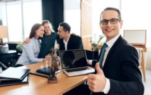 Lawyer shows thumb up while sitting at table with family at background